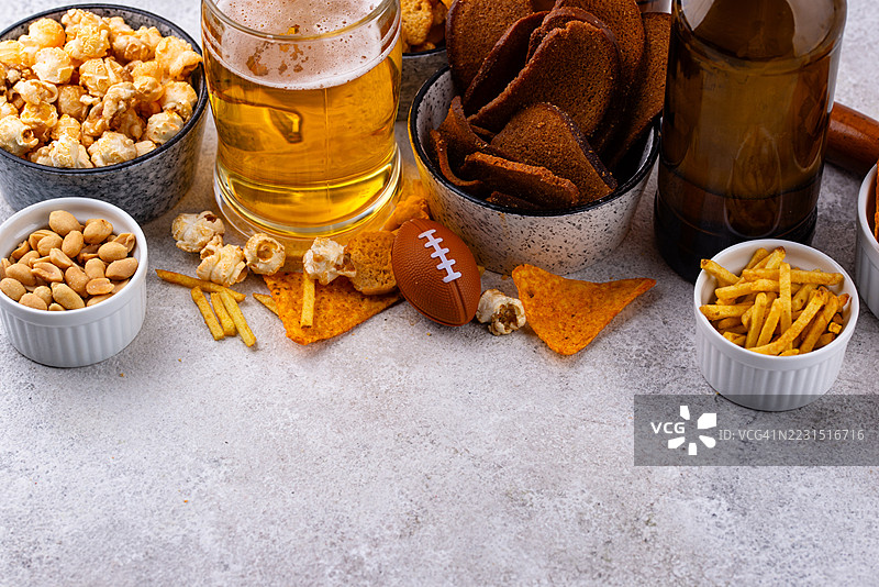 桌上摆放着各种零食和啤酒，旁边还有一个迷你足球图片素材