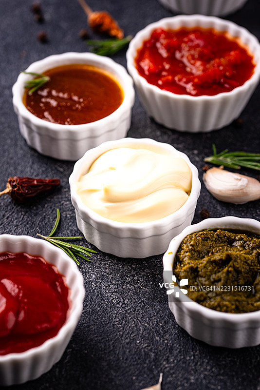 深色表面上的陶瓷碗中盛放的各种酱汁图片素材