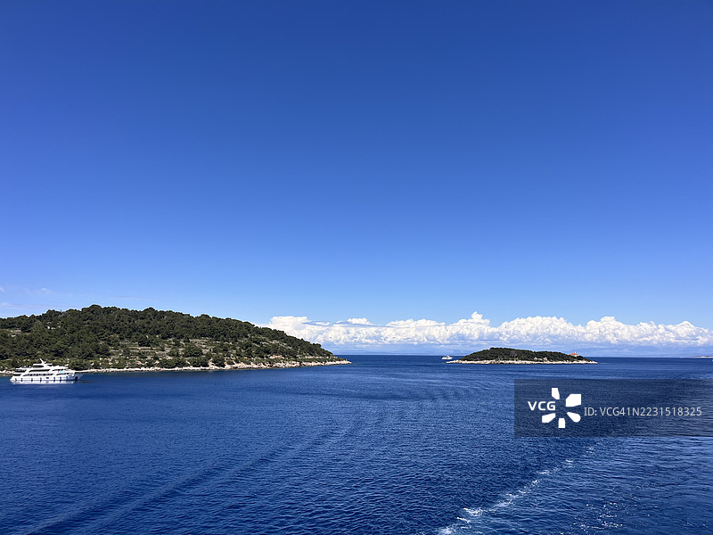 宁静的海岸风景，岛屿和游艇在晴朗的蓝天下图片素材