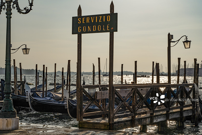 威尼斯日落时停靠在码头的贡多拉，意大利图片素材