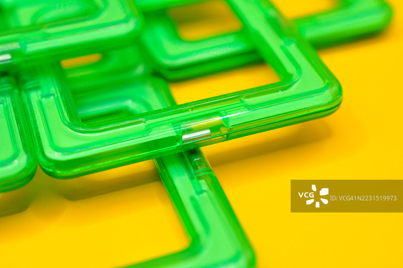 绿色塑料玩具零件在鲜艳的黄色背景上图片素材