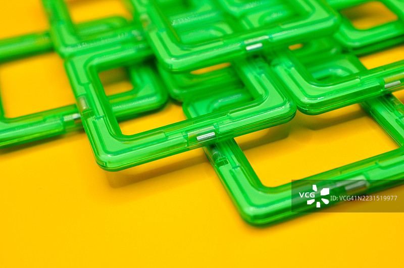 绿色玩具积木排列在鲜艳的黄色背景上图片素材