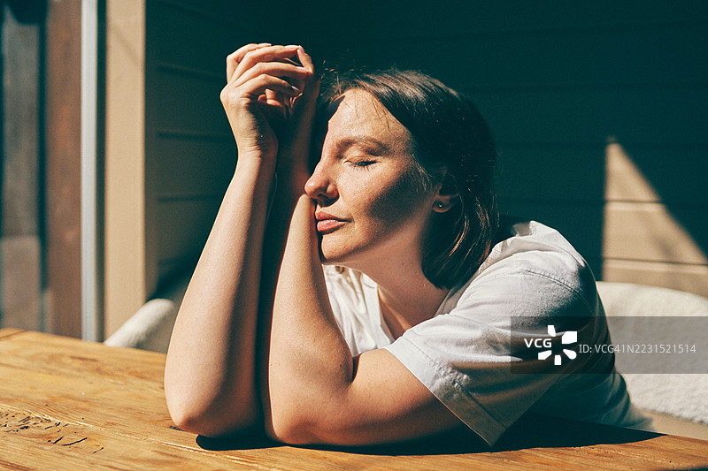 女人在木质露台桌上享受阳光的放松时光图片素材