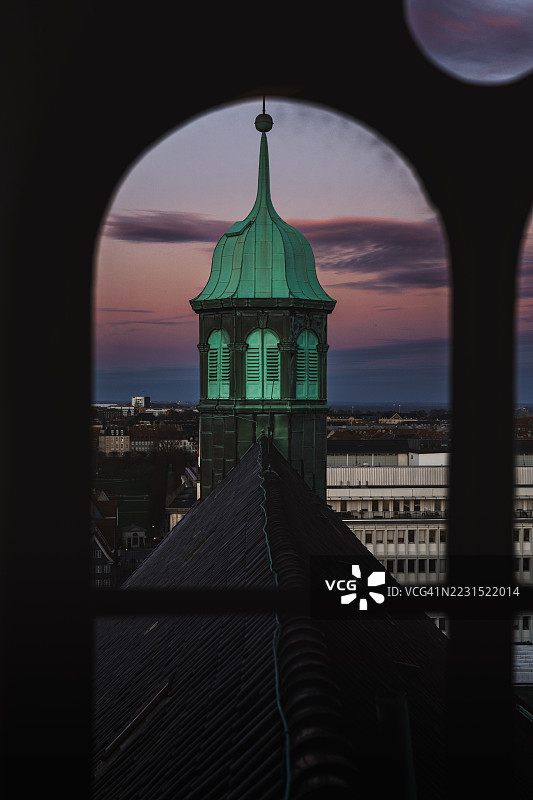 日落时分，丹麦教堂尖塔透过窗户框架。图片素材