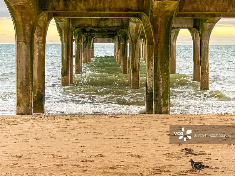 在码头下，海浪拍打着沙滩图片素材