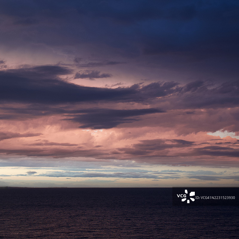 日落时分，平静的海面上空出现戏剧性的天空景象图片素材