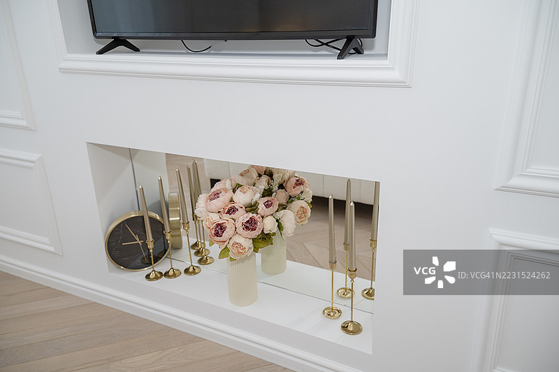 优雅的玫瑰花束放在带蜡烛和时钟的镜面架子上图片素材