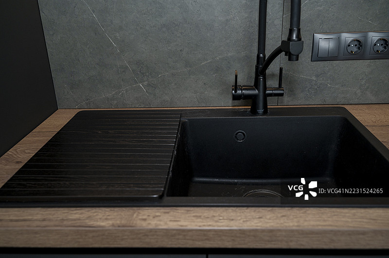 现代厨房水槽，配有黑色水龙头和木质台面图片素材