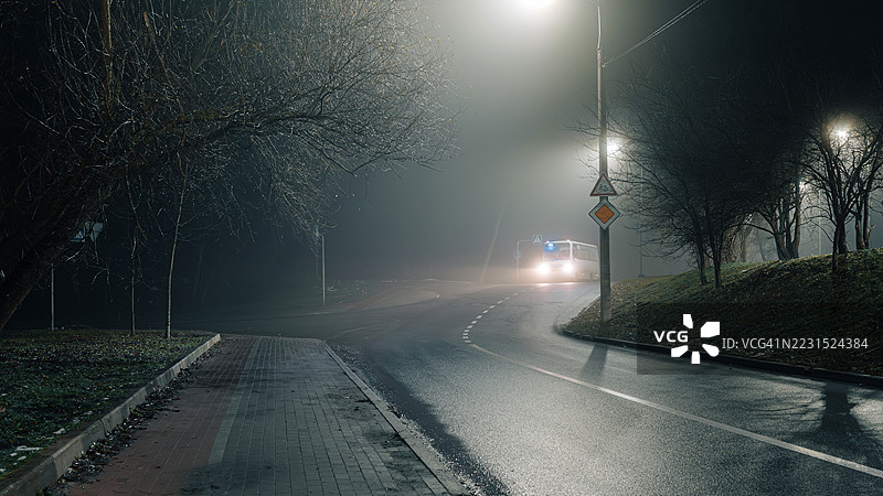 雾蒙蒙的夜晚道路，路灯和一辆公交车图片素材