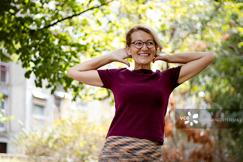 成熟的金发女性在城市公园做拉伸运动图片素材