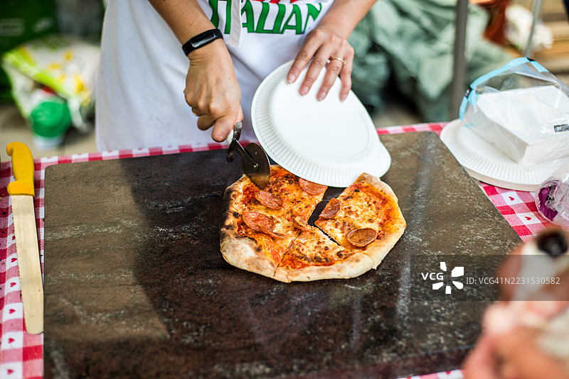 在食品摊位上用披萨刀切玛格丽塔披萨图片素材