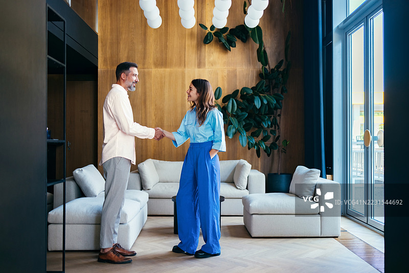 两位专业人士在现代办公室内握手图片素材