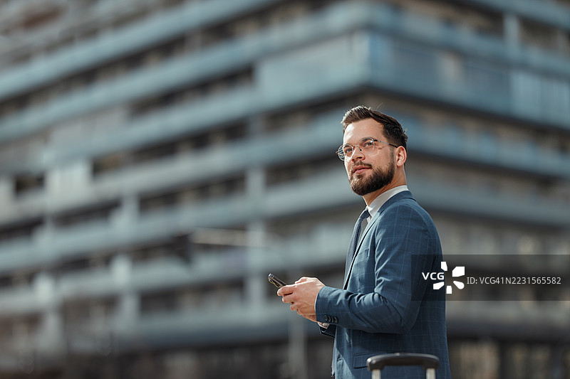 户外微笑的商人使用智能手机图片素材