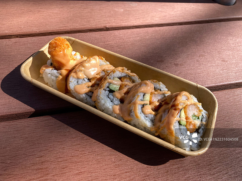 装有虾炸猪排、黄瓜、鳄梨、辣味美乃滋和照烧酱的外卖寿司盒图片素材