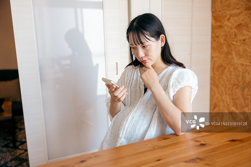 孕妇在智能手机上查看健康管理应用程序图片素材