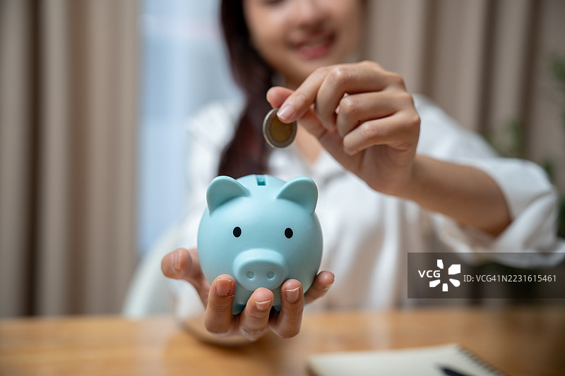 女人的手将硬币放入储蓄罐中以储蓄。财富与繁荣。成功的投资与存款。储蓄与财务规划的概念。图片素材