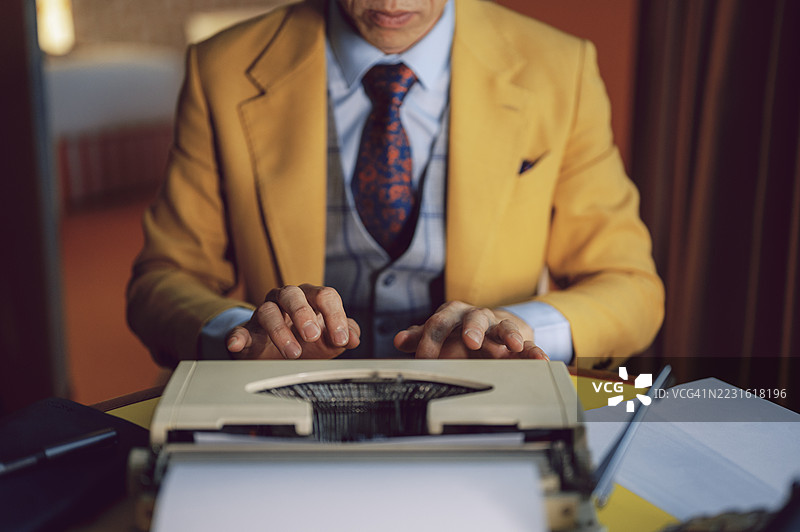 亚洲男性的手在复古打字机上打字的特写镜头图片素材