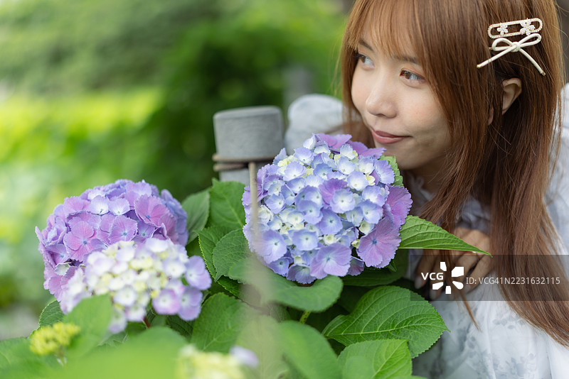 穿着浅蓝色裙子的年轻女性游客坐在公园里欣赏风景图片素材