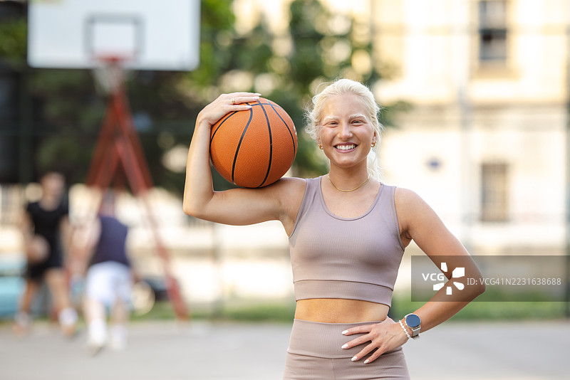 户外微笑女性手持篮球的肖像图片素材