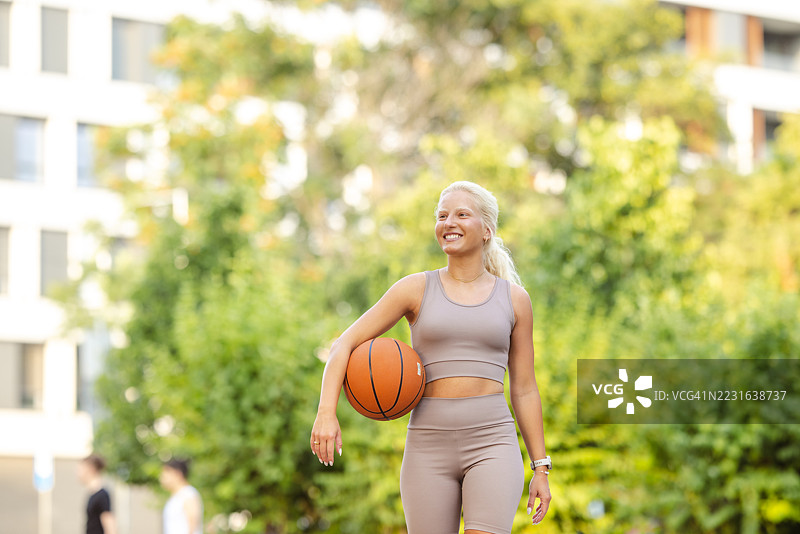 年轻女性在户外打篮球，心情运动而愉快图片素材