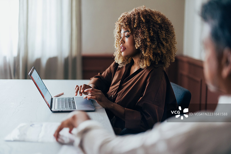 在协作会议环境中使用笔记本电脑的女商人图片素材