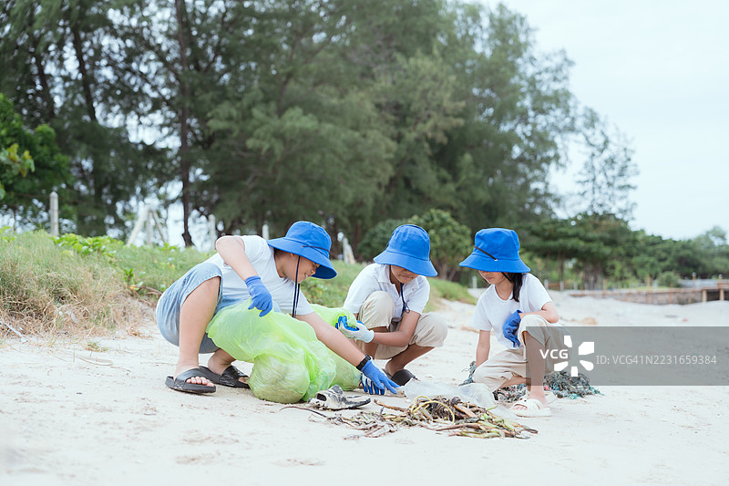 孩子们在海岸地区的阴天参加海滩清理活动，以保护海洋生物和自然环境。图片素材