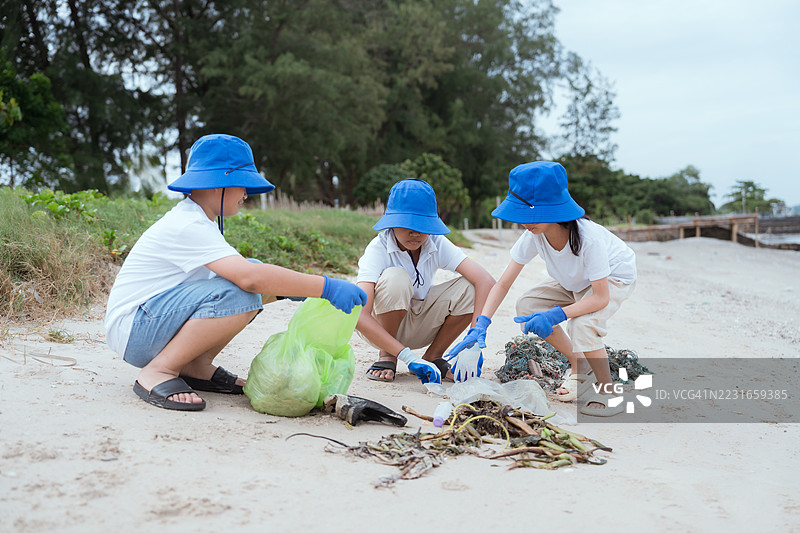 孩子们在海岸地区的阴天参加海滩清理活动，以保护海洋生物和自然环境。图片素材