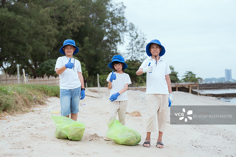 孩子们在阳光明媚的日子里参加海滩清理活动，宣传环保意识图片素材