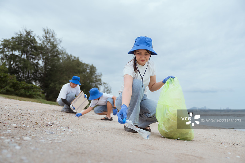 社区成员在阴天的城市附近参加海滩清理活动图片素材