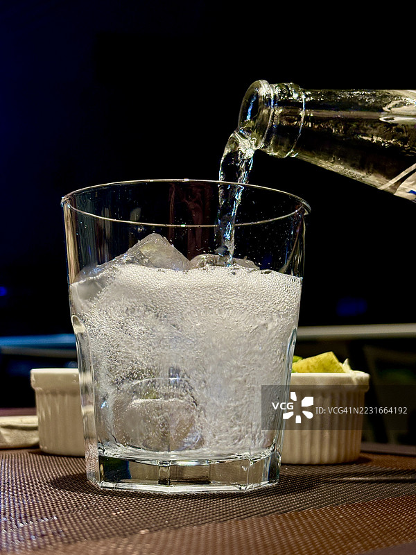 苏打水倒入伏特加杯中。图片素材