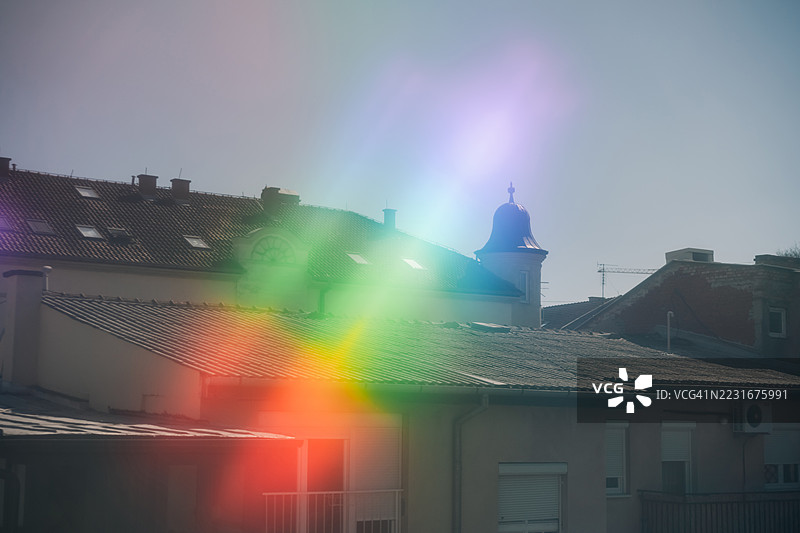 复古照片，展示带有塔楼的老屋顶，彩虹形的光晕。图片素材