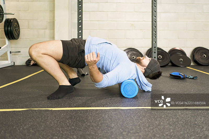 运动员在健身房使用泡沫轴拉伸背部肌肉图片素材