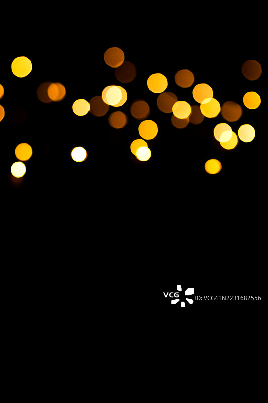 黑色背景上的金色散景灯光，留有空白空间。图片素材
