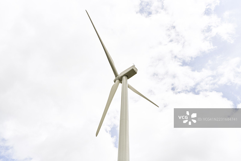 在多云的天空下，风力涡轮机正在产生清洁能源图片素材