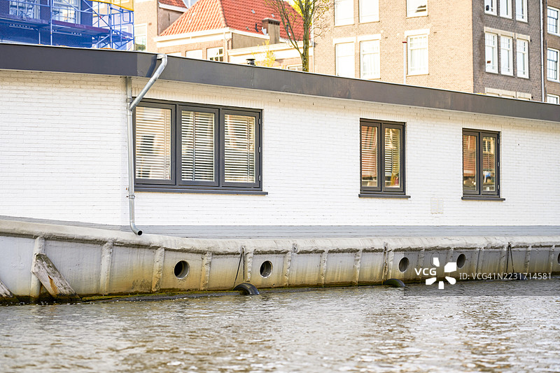 白色房船停靠在阿姆斯特丹运河上，窗户是深色的。图片素材