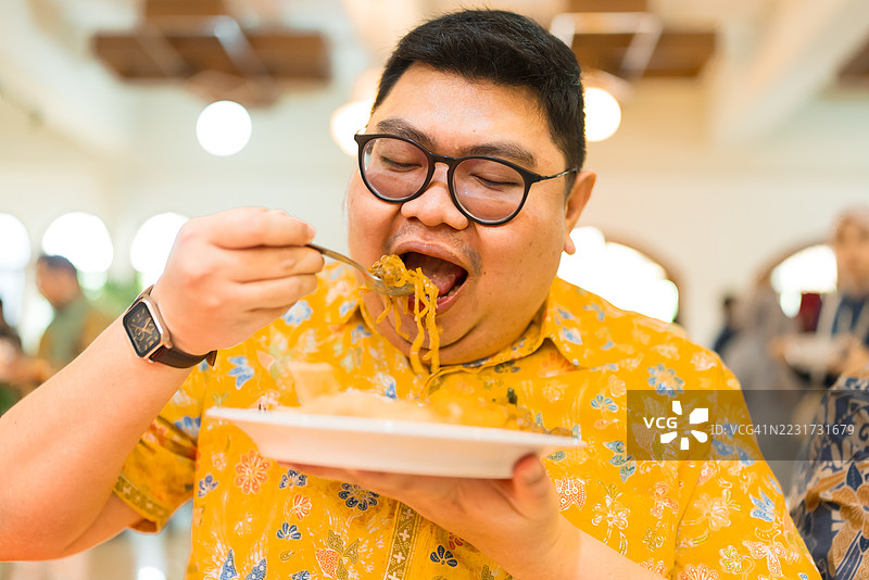 正面视角的超重男性享受他自制的意大利面和炸鸡图片素材