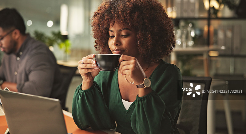 年轻职业女性在现代办公室环境中喝咖啡工作图片素材