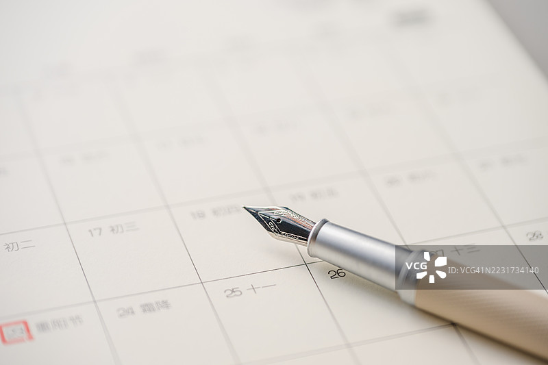 钢笔在桌面日历上。图片素材