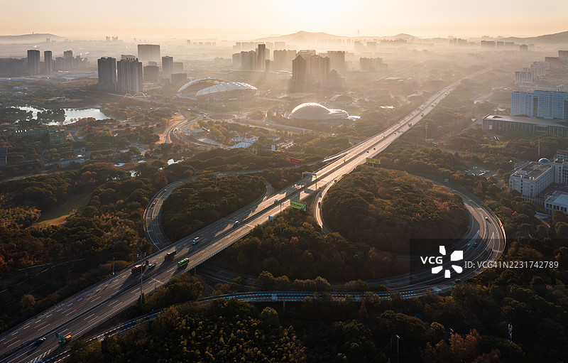 雾霭晨曦中的城市区域鸟瞰图，展现高速公路和建筑物。图片素材
