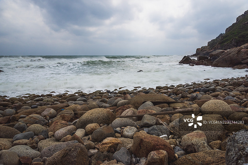 多云天空下的岩石海岸和波涛汹涌的海景图片素材