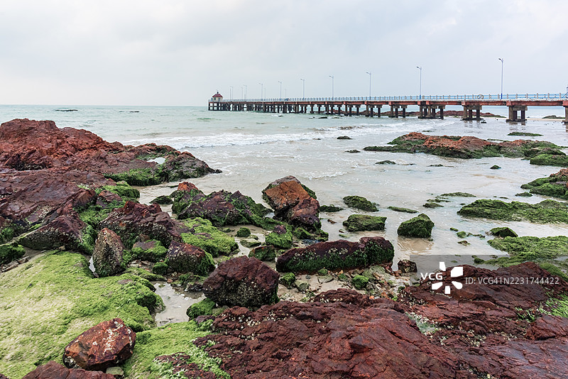 海边景色，岩石和长长的码头在阴云密布的天空下图片素材