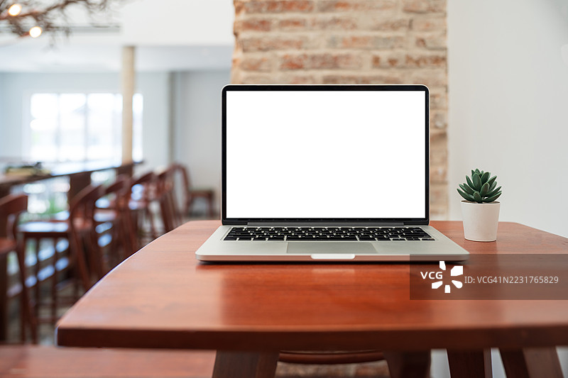 咖啡馆背景下桌子上的笔记本电脑空白屏幕。咖啡店桌子上的笔记本电脑空白屏幕，背景模糊。图片素材