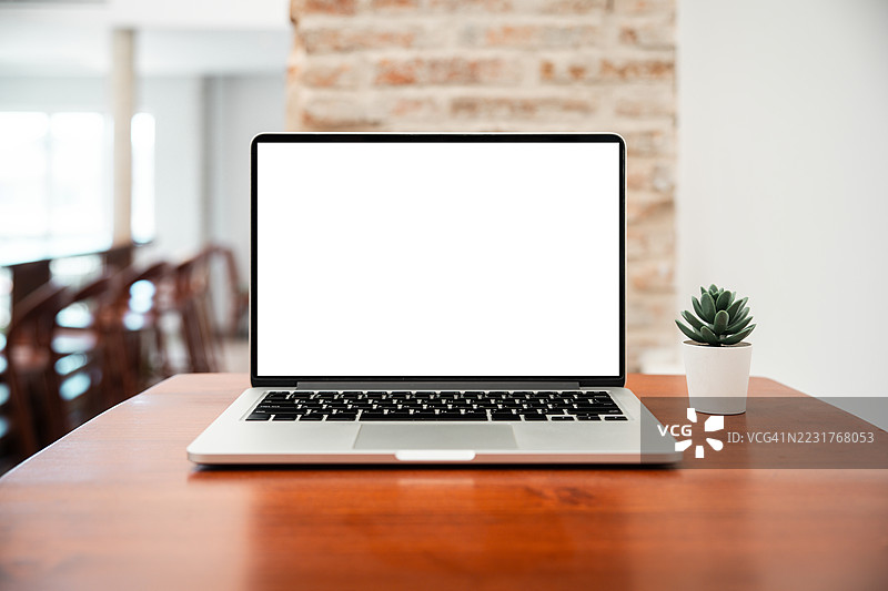 咖啡馆背景下桌子上的笔记本电脑空白屏幕。咖啡店桌子上的笔记本电脑空白屏幕，背景模糊。图片素材