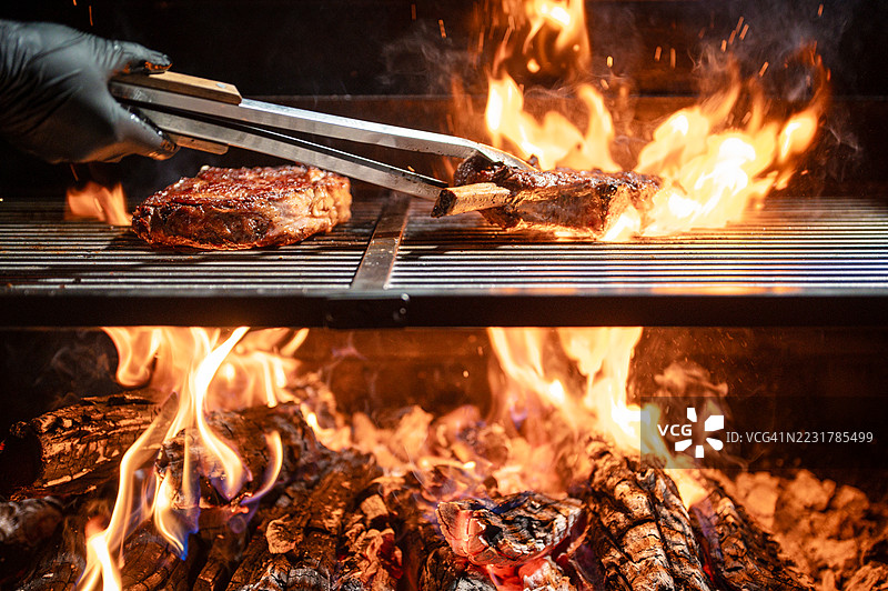在乡村烧烤环境中，牛排在明火上烤制图片素材