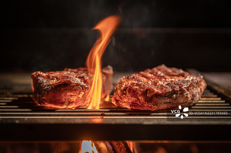 火焰上烤制的牛排，香气四溢，滋滋作响的烧烤架上图片素材