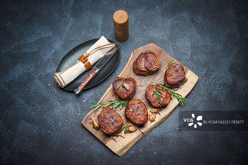 香草大蒜烤牛排摆放在质朴的木板上图片素材