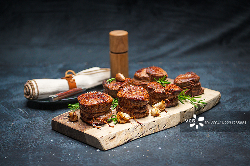 美味的菲力牛排放在带有迷迭香的乡村砧板上图片素材