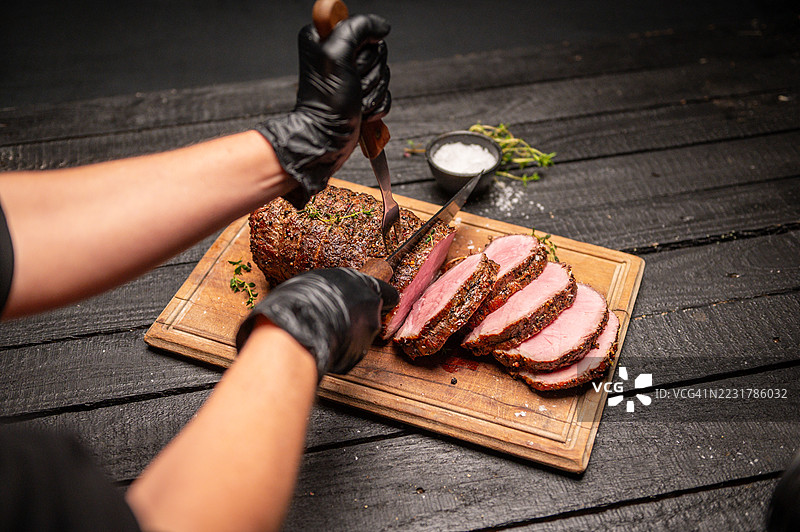 厨师在木砧板上切割调味烤牛肉图片素材