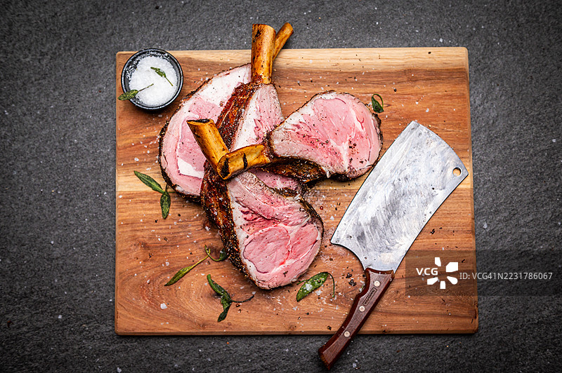 带有乡村风格刀具的多汁切片牛肋骨放在木砧板上图片素材