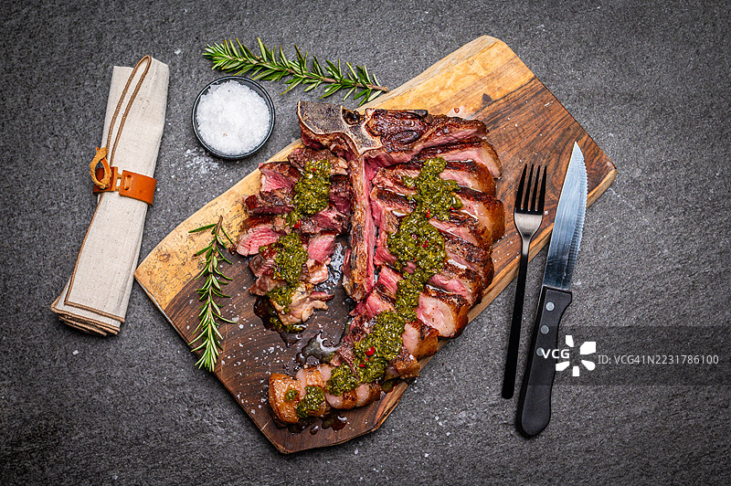 美味的烤牛排配香菜酱，摆放在木板上图片素材